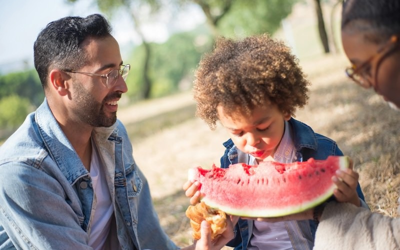 a little boy eating watermelon outside