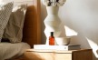 a vase with cotton stems on a bedside table